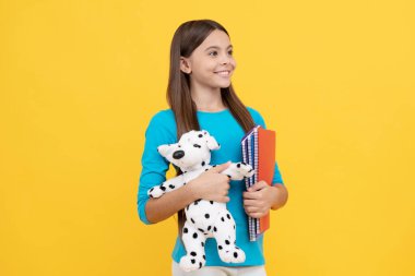 Mutlu çocuk not defteriyle ödev yapacak. Oyuncak köpek tutan genç bir öğrenci. Eğitim kavramı. Kitapçığı olan liseli kız. Okula dönüyorum. Genç kız ders çalışmaya hazır. çocukluk mutluluğu.