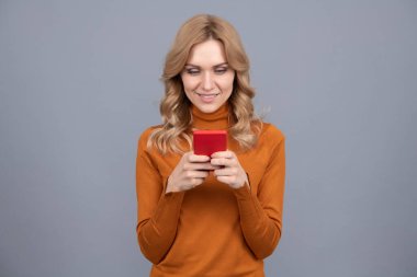 Güzel kadın cep telefonu aygıtı gri arkaplan, SMS kısa mesaj.