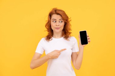 Özelliklerle dolu. Cep telefonunu işaret ederek. Mobil aygıtı göster. Ürün sunumu, kopyalama alanı. Şaşırmış bir kadın online bankacılık kullanıyor. Evden alışveriş. Siber pazartesi. Akıllı telefonlu kızıl saçlı kız..