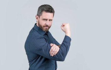 Mature man bend arm in L-shape with fist pointing upwards obscene gesture grey background, fuck you, copy space.