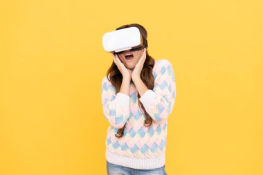 Büyülenmiş genç kız sanal gerçeklikte eğitim için geleceğin teknolojisini kullanarak video gözlük takıyor..