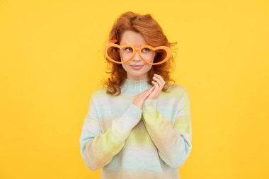 Model. Sarı arka planda güzel bir bayan. Parti gözlüklü komik kızıl kadın. Eğlence zamanı. Gülümseyen kız gözlük takıyor. Doğum günü partisi kutlaması. Pozitif ol. pozitif duygular.