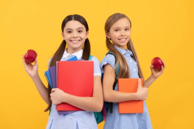 Kitapları olan mutlu öğrenciler vitaminli organik elma sarısı arka plan, okul kahvaltısı.