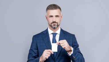 Takım elbiseli kendine güvenen işadamı fotokopi alanı ve kartvizit için kredi kartı gösteriyor..