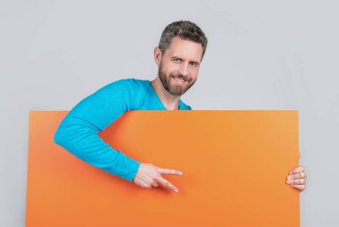 Reklam için fotokopi alanı olan boş turuncu pankartın arkasında olgun sakallı bir adam barış jesti yapıyor..