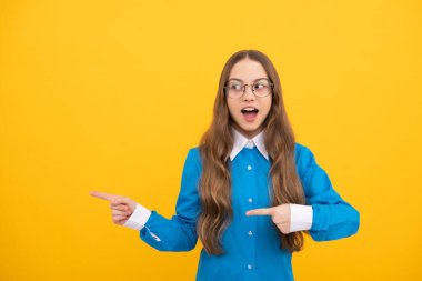 Eğitim yeni bir adres aldı. Şaşkın çocuk sarı arka planı işaret ediyor. Okula dönelim. Reklam için işaret. İşaret işareti, boşluğu kopyala.