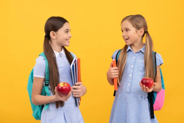 幸せな子供たちは学校に戻って健康的な食事のための本やリンゴを保持黄色の背景 — ストック写真