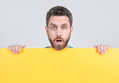 Pazarlama tasarımı ve tanıtım için fotokopi alanı olan boş sarı pankartın arkasında yetişkin sakallı bir adam var..