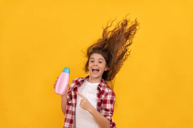 Kozmetik ürünleri sunuyorum. Güzellik. Çocuk duş jeli kullanıyor. Şampuan şişeli mutlu genç kız. Kuaförde saç şampuanlıyordum. Saç kremi kullanan bir çocuk. Uzun kıvırcık saçlı. Günlük alışkanlıklar ve kişisel bakım.