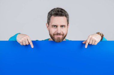Adam duyuru yapıyor. Erkek, kağıt çarşafın arkasında. Yararlı bilgi için yer. kopyalama alanı. İşaret parmağı. Terfi ve yaratıcılık için bir yer. Pazarlama tasarımın için. Kağıt pankartıyla sakallı adam.