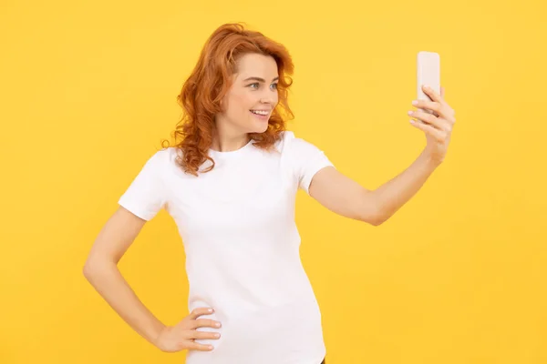 快乐的女孩对着手机笑黄色背景 视频自拍 — 图库照片
