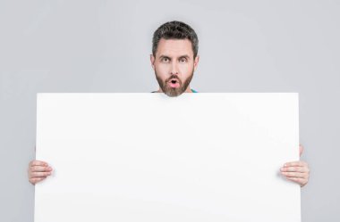 Yararlı bilgi için yer. kopyalama alanı. Terfi ve yaratıcılık için bir yer. Pazarlama tasarımın için. Kağıt pankartıyla şok olmuş sakallı adam. Şaşırmış adam duyuru yapıyor. Erkek kağıt çarşaf arkasında.