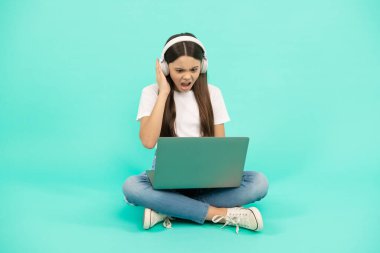 Şok olmuş çocuk nüfuzlu kişi video görüşmesi için kablosuz bilgisayar kullanıyor ya da kulaklıkla Webinar dinliyor, blog yazıyor.