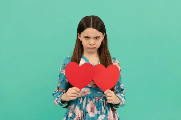 so sad. unhappy child with red hearts. happy valentines day. be my valentine. heart symbol of love. lovely beauty. pretty kid cupid. mothers or fathers day holiday. expressing human emotions.