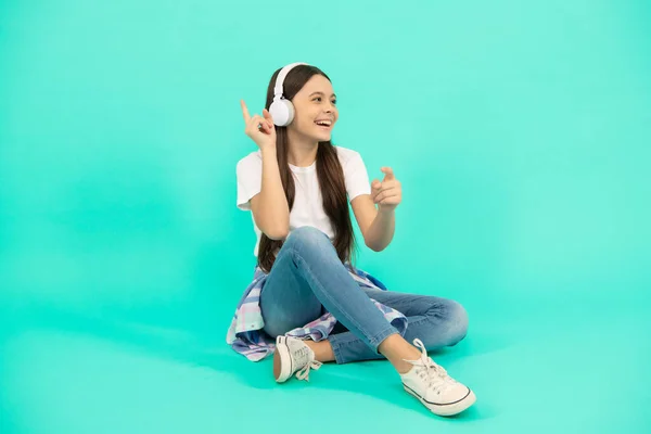 歌おう 現代のイヤホンの子供です オンライン教育です 学校に戻って ヘッドフォンで幸せな10代の女の子 音楽を聴け 無線ヘッドセット装置付属品 新しい技術だ 幼少期の発達 — ストック写真