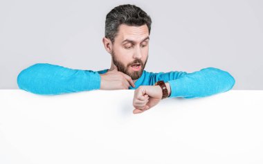 Şok adam boş beyaz afiş arkasında reklam ve alışveriş saati için fotokopi alanı ile zamanı kontrol ediyor..