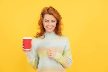 Kadın plastik bardağı işaret ediyor. Günaydın. Mutluluğu ifade et. pozitif duygular. Zevkin portresi. Mutlu kızıl kadın kahve içer. İçeceklerinizi alın. Neşeli kız çay içiyor..