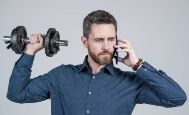İletişim. Dambılı yakışıklı iş adamı telefonda konuşuyor. Dijital spor. Akıllı telefon ve halterli patron. Konuşma. Ciddi bir iş adamı iş görüşmesi yapıyor. çevik iş başarısı.