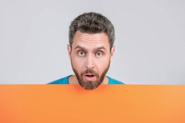 Turuncu siyah pankartın arkasında bilgi için fotokopi alanı olan olgun sakallı bir adam, satıcı..