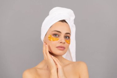 Terry havlusu olan şehvetli kadın cilt için altın göz bandı kullanır..