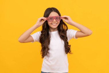 Yeni stili. Büyüleyici gözlüklü, sahte elmaslı mutlu bir çocuk. Eğlenceli genç kız eğleniyor. Gözlüklü neşeli çocuk. Moda aksesuarı. Deliriyor. çocukluk mutluluğu. Şık parti görünüşü.