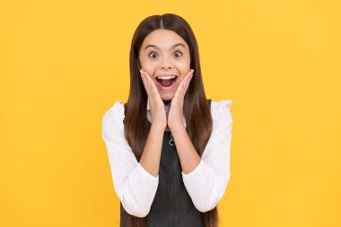 Şaşkın ilkokul çocuğu üniformalı sarı arka plan, sürpriz.