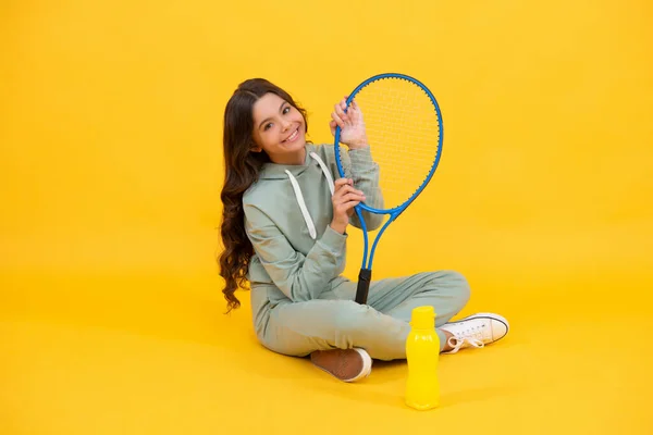 Glad barn sitta i sportkläder med badminton racket och vattenflaska, aktiv sport. — Stockfoto