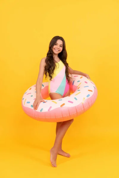 Happy kid in swimming suit with doughnut inflatable ring on yellow background, childhood. — Stock Photo, Image