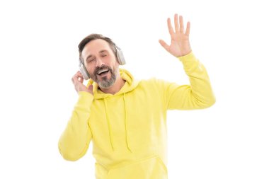 Kapüşonlu sakallı ve bıyıklı neşeli olgun bir adam. Beyaz, kablosuz teknolojiyle izole edilmiş kulaklıklı müzik ya da ses kitabı..