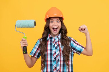 Şaşırmış, kıvırcık saçlı, miğferli, boya silindirli, süslemeli çocuk.