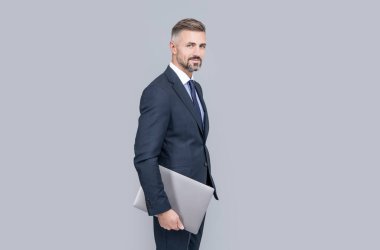 Resmi takım elbiseli, gri saçlı olgun bir ofis çalışanı. Bilgisayarı var, çevik iş yapıyor.