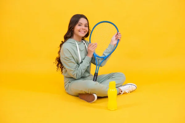 Leende barn sitta i sportkläder med squash racket och vattenflaska på gul bakgrund, sport — Stockfoto