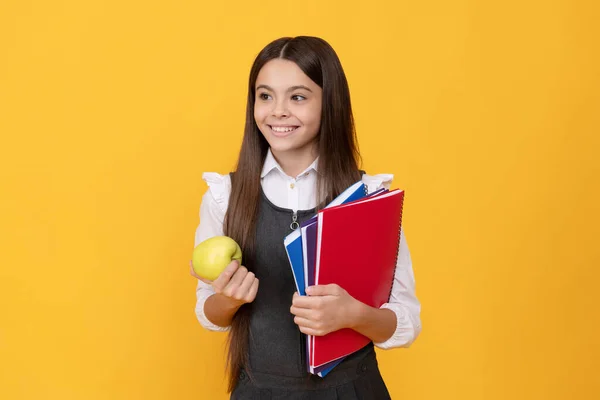 Happy girl dziecko z powrotem do szkoły gospodarstwa jabłko i książki żółte tło, dzień wiedzy — Zdjęcie stockowe