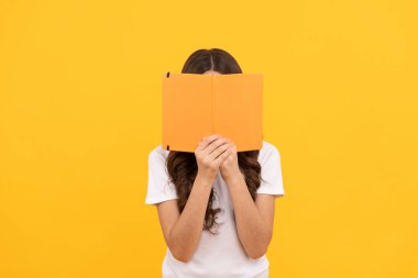 Okumaya hazır gülümseyen okul çocuğu kitap ve bilginin arkasına saklan.