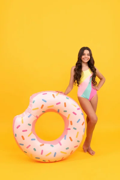 Пляжна дівчина-підліток у купальнику з пончиком надувний кільце на жовтому фоні, пляжний аксесуар . — стокове фото
