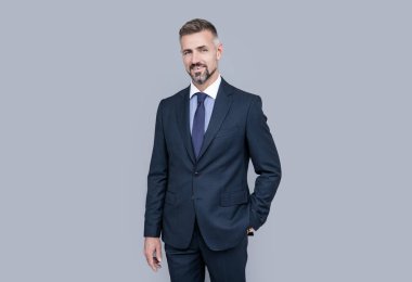 Gri saçlı, resmi takım elbiseli, karizmalı olgun bir lider.