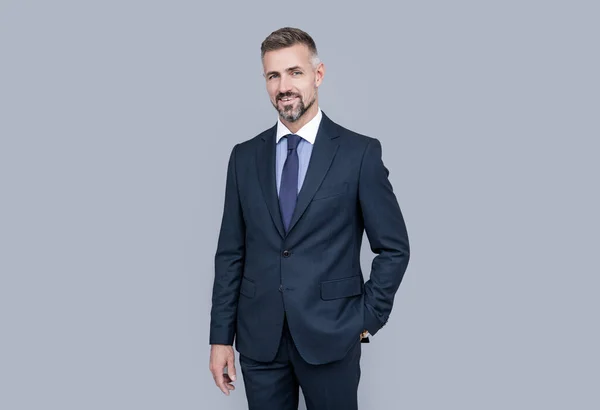 Gri saçlı, resmi takım elbiseli, karizmalı olgun bir lider.
