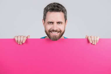 Erkek, kağıt çarşafın arkasında. Yararlı bilgi için yer. kopyalama alanı. Terfi ve yaratıcılık için bir yer. Pazarlama tasarımın için. Kağıt pankartıyla neşeli sakallı adam. Mutlu adam duyuru yapıyor..