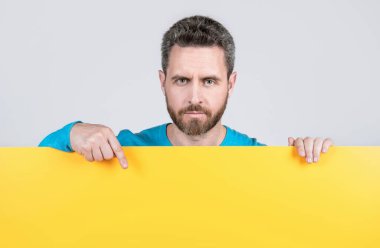 Pazarlama tasarımın için. Kağıt pankartıyla sakallı adam. Adam duyuru yapıyor. Erkek, kağıt çarşafın arkasında. Yararlı bilgi için yer. kopyalama alanı. İşaret parmağı. terfi ve yaratıcılık için yer.