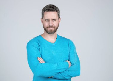 Saf güven. Tıraşsız, kıllı ve bıyıklı adam. Kendine güvenen olgun bir adam. Sıradan giyinen yakışıklı adamın saçları kırlaşmış. Gri arka planda başarılı bir adam. Erkeklerin güzellik stili. Erkek modası