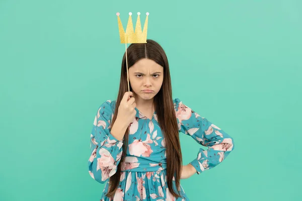 Angry selfish girl hold booth crown over head keeping arm akimbo blue background, egoist — Stock Photo, Image