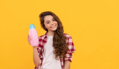 Güzellik. Çocuk duş jeli kullanıyor. Şampuan şişeli mutlu genç kız. Kuaförde saç şampuanlıyordum. Saç kremi kullanan bir çocuk. Uzun kıvırcık saçlı. Günlük alışkanlıklar ve kişisel bakım. Kozmetik ürün sunumu.