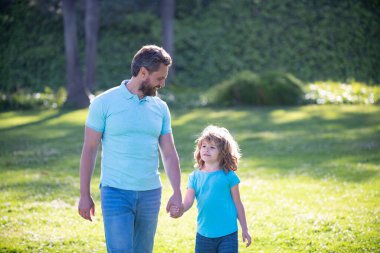 Anne ve babası küçük çocuğa çimlerde yol gösteriyor. Baba ve çocuk yaz günü.