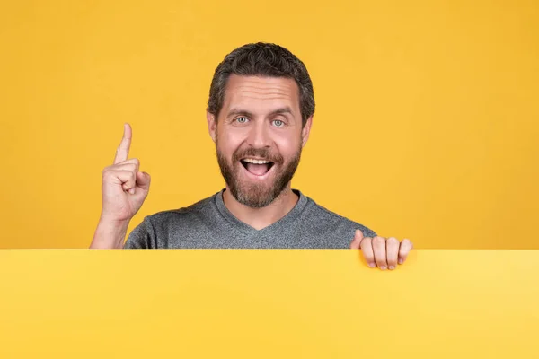 Happy bearded man raised finger inspired with idea behind yellow paper for copy space, advertisement — Stock Photo, Image