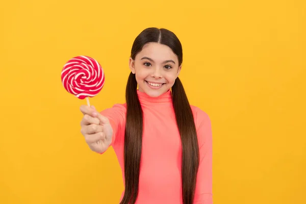 Gelukkig tiener meisje met lolly snoep op stok op gele achtergrond, candy shop — Stockfoto