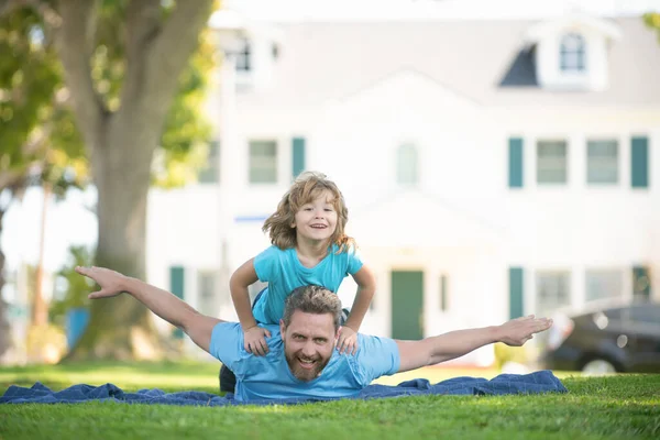 Finge volar. Padre e hijo se divierten tumbados en la manta. Día de diversión familiar. Vacaciones de verano — Foto de Stock