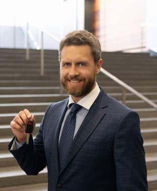 Mutlu sakallı adam takım elbiseli işadamı araba ya da evin anahtarı, gayrimenkul.