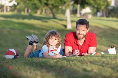 Baba ve oğul parkta çimenlerde rahatlar çizim yapmayı öğrenir, aile hafta sonu