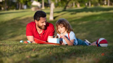 Baba oğul açık havada resim çiziyor. Babalar günün kutlu olsun. Mutlu bir aile. Baba ve çocuk çimenlerde rahatlayın.