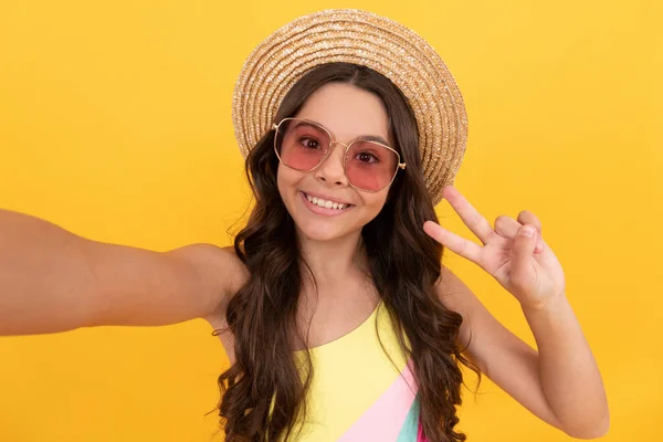 Heureux adolescent fille en été paille chapeau et lunettes faisant selfie sur fond jaune, selfie — Photo